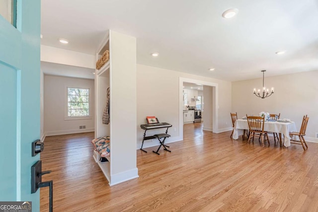 foyer entrance with an inviting chandelier, light wood-style floors, baseboards, and visible vents