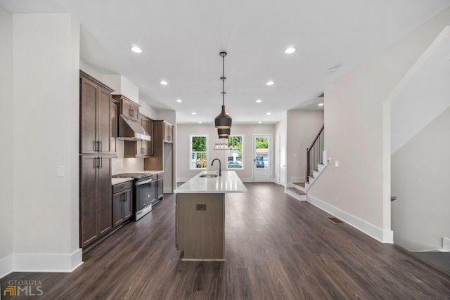 kitchen with dark wood-type flooring, a sink, under cabinet range hood, light countertops, and gas range