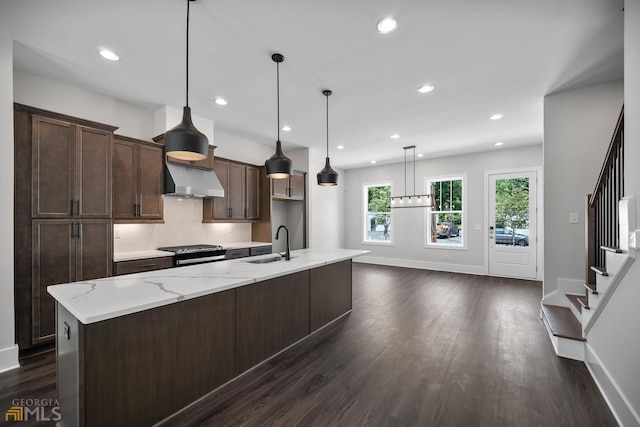 kitchen with a spacious island, under cabinet range hood, dark brown cabinetry, electric range, and a sink