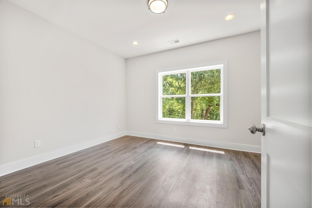 spare room with wood finished floors, recessed lighting, baseboards, and visible vents