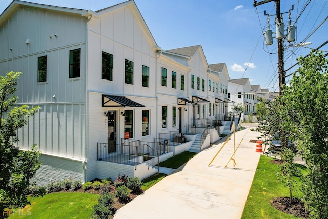 view of front facade featuring brick siding, a residential view, and board and batten siding