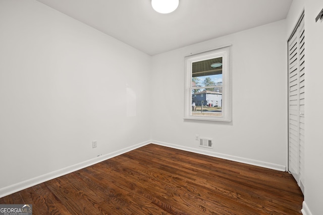 spare room with visible vents, baseboards, and dark wood-style floors