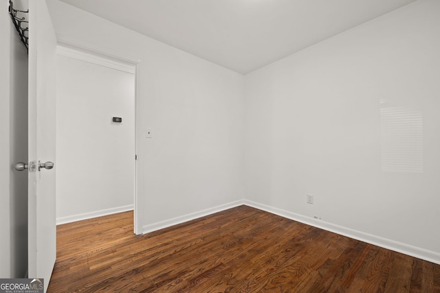 spare room featuring baseboards and dark wood-style flooring