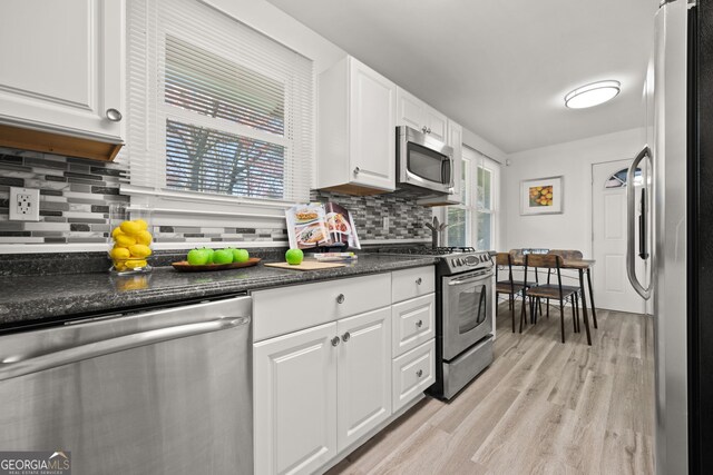 kitchen featuring white cabinets, tasteful backsplash, light wood finished floors, and stainless steel appliances