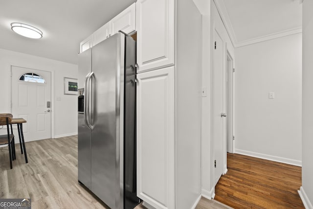kitchen with white cabinetry, stainless steel fridge with ice dispenser, baseboards, and light wood finished floors