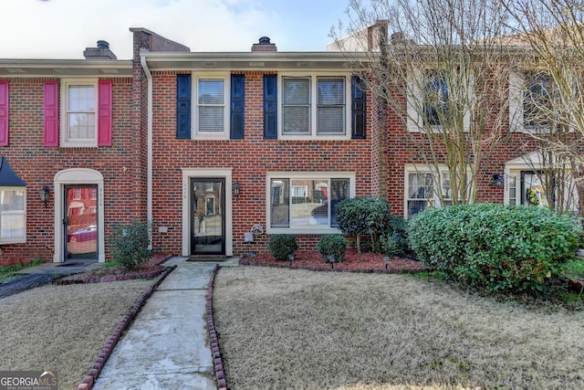 townhome / multi-family property featuring brick siding and a chimney