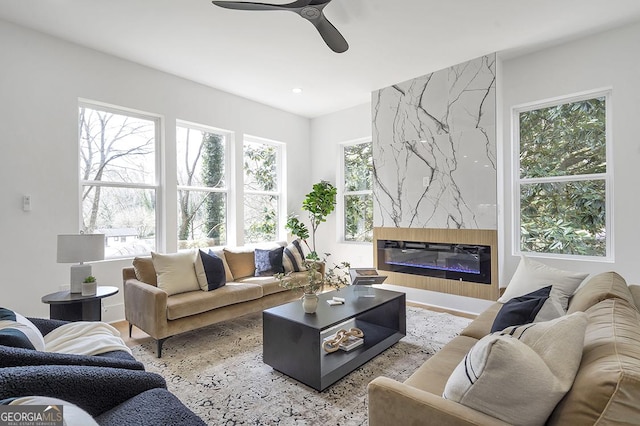 living area with a high end fireplace, ceiling fan, and wood finished floors