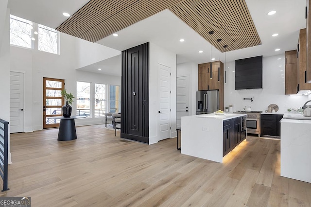 kitchen with light wood finished floors, premium appliances, a kitchen island, recessed lighting, and light countertops