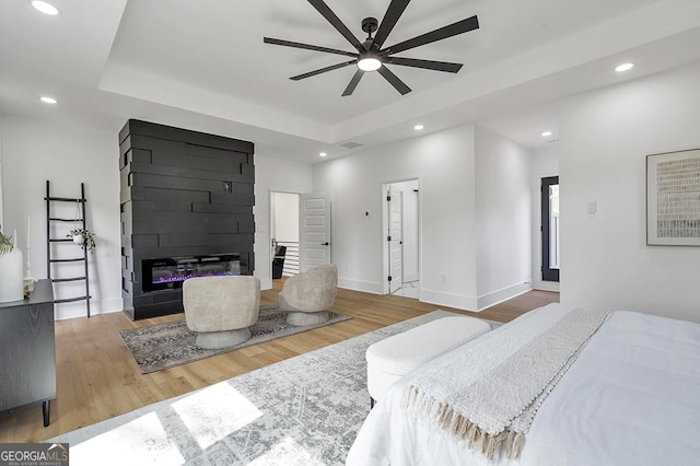 bedroom with recessed lighting, a raised ceiling, and wood finished floors