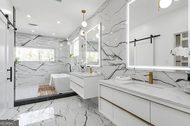 full bathroom with marble finish floor, a sink, recessed lighting, a freestanding bath, and stone wall