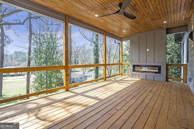 unfurnished sunroom featuring wooden ceiling, a healthy amount of sunlight, and ceiling fan