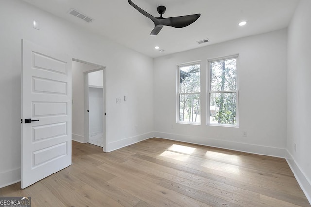 unfurnished room featuring light wood-style floors, a ceiling fan, visible vents, and baseboards