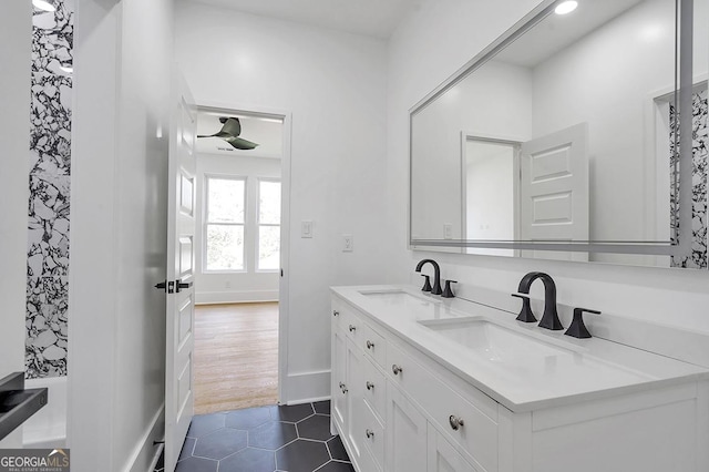 full bathroom featuring a sink, baseboards, double vanity, and tile patterned floors