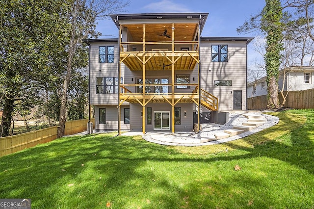 back of house with a lawn, a ceiling fan, a fenced backyard, a balcony, and a patio area