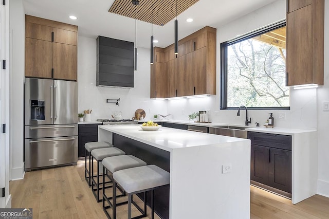 kitchen with light wood-type flooring, a healthy amount of sunlight, stainless steel refrigerator with ice dispenser, and a sink