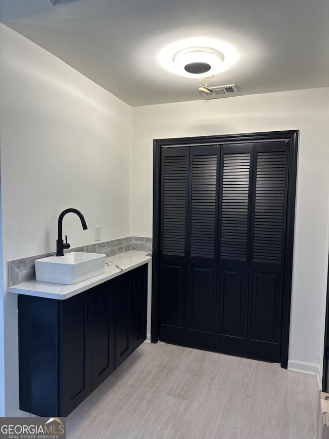 bathroom with wood finished floors, visible vents, a closet, and a sink