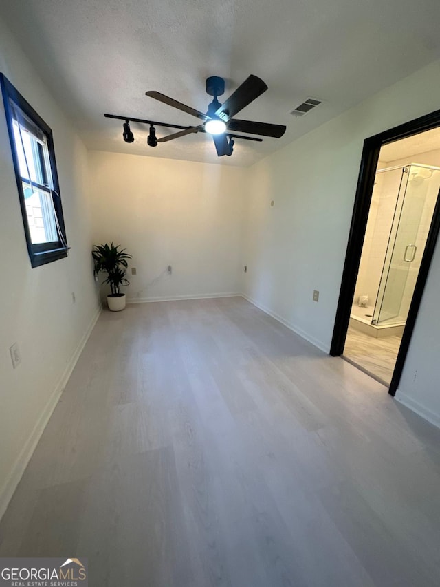 unfurnished bedroom featuring visible vents, baseboards, rail lighting, light wood-style floors, and a ceiling fan