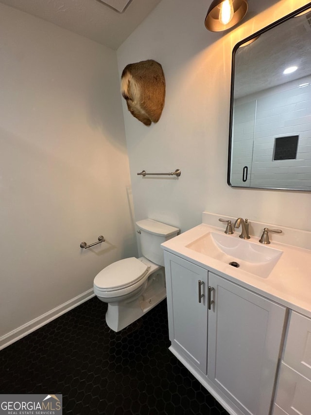 bathroom with toilet, vanity, and baseboards