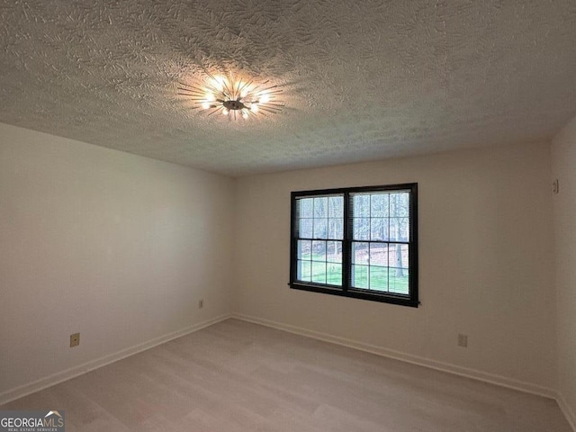 unfurnished room with baseboards, light wood-style floors, and a textured ceiling