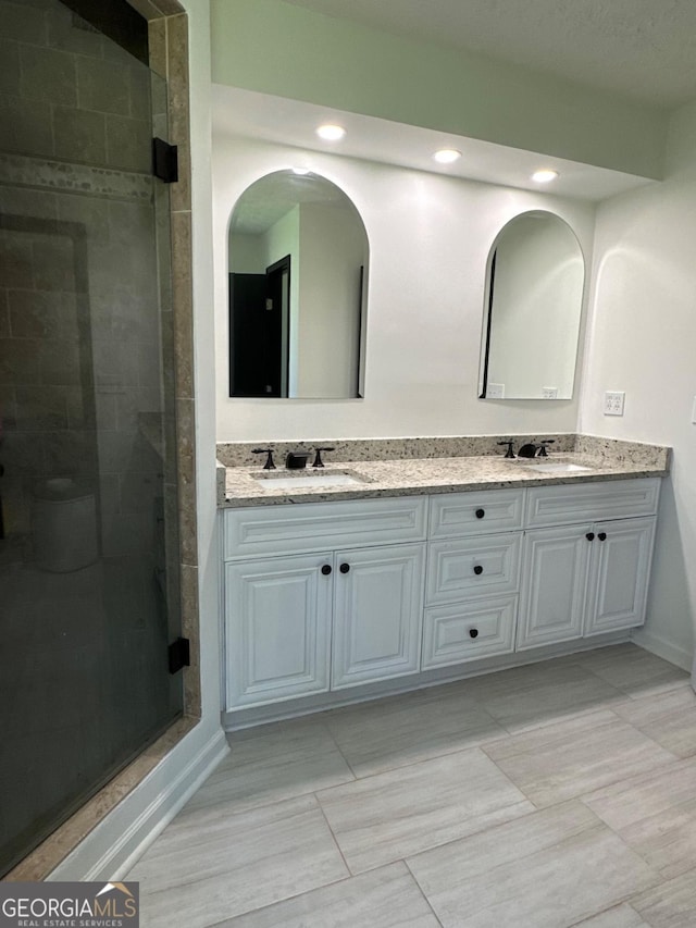 bathroom featuring double vanity, recessed lighting, a stall shower, and a sink