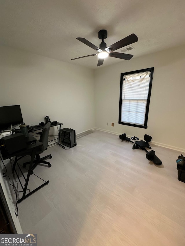 office area with visible vents, a ceiling fan, light wood-type flooring, and baseboards