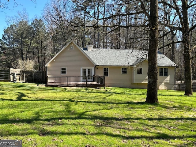 rear view of property featuring fence, french doors, a chimney, a yard, and a deck