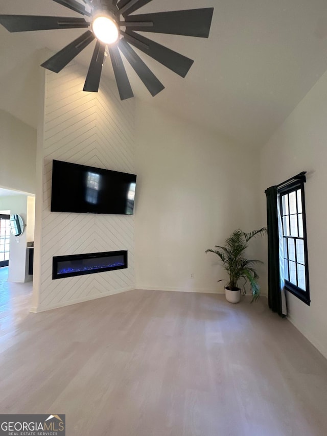 unfurnished living room with plenty of natural light, high vaulted ceiling, wood finished floors, and a fireplace