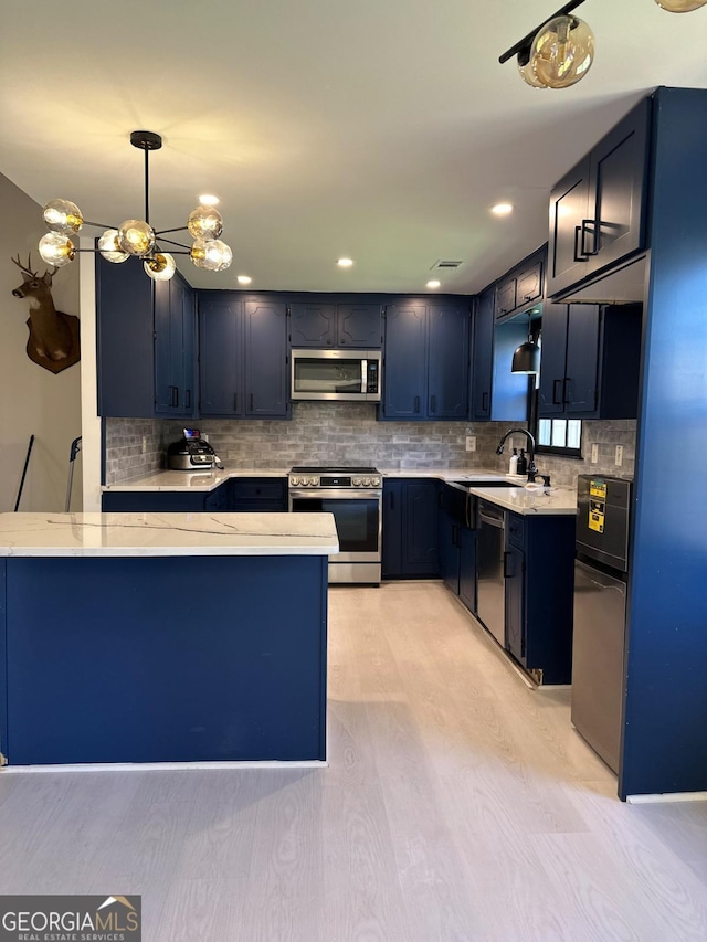 kitchen with light stone countertops, a sink, stainless steel appliances, light wood-style floors, and tasteful backsplash