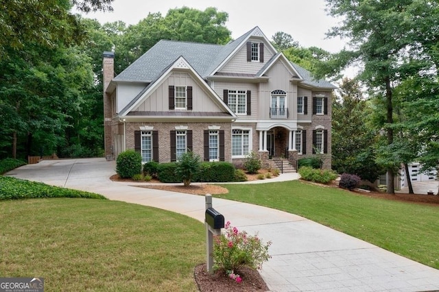 craftsman-style house featuring brick siding, board and batten siding, a shingled roof, a front lawn, and a chimney