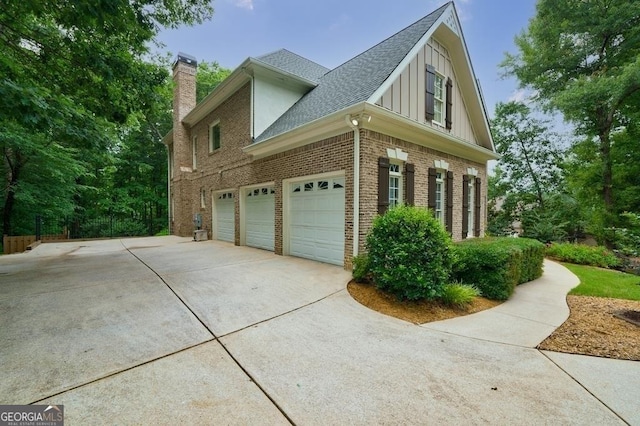 view of property exterior featuring brick siding, concrete driveway, roof with shingles, a chimney, and an attached garage