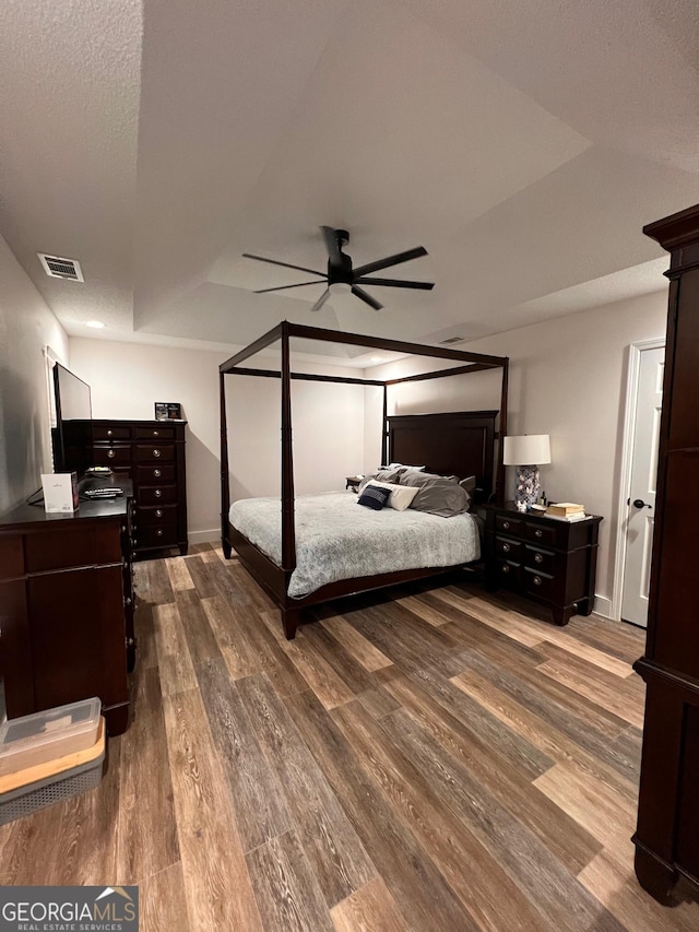 bedroom with visible vents, baseboards, dark wood-type flooring, and a ceiling fan