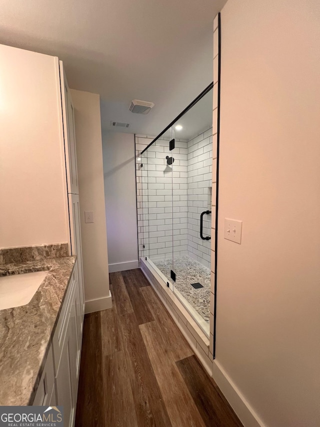 bathroom featuring vanity, wood finished floors, baseboards, visible vents, and a shower stall