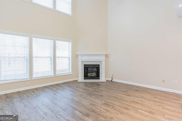 unfurnished living room with a glass covered fireplace, light wood-style floors, and baseboards