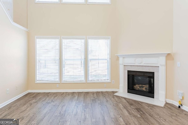 unfurnished living room with a fireplace, baseboards, and wood finished floors