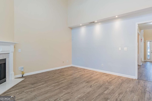 unfurnished living room with wood finished floors, a fireplace, and baseboards