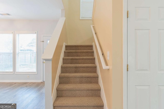 staircase with visible vents, baseboards, and wood finished floors