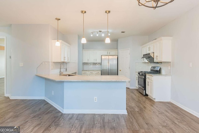 kitchen featuring a sink, stainless steel appliances, a peninsula, and wood finished floors