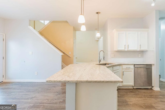 kitchen with a sink, stainless steel dishwasher, white cabinetry, light wood-style floors, and a peninsula