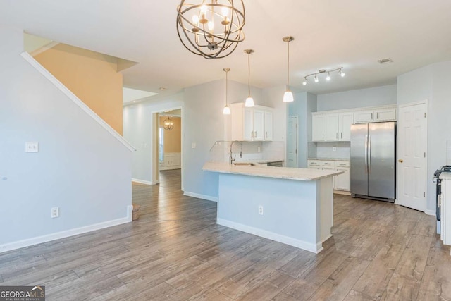 kitchen featuring a chandelier, freestanding refrigerator, light wood-style floors, white cabinetry, and a sink