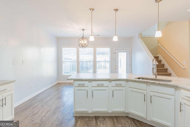 kitchen featuring pendant lighting, baseboards, light wood-type flooring, and a sink