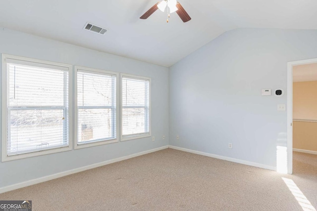 empty room featuring a ceiling fan, baseboards, visible vents, carpet floors, and vaulted ceiling