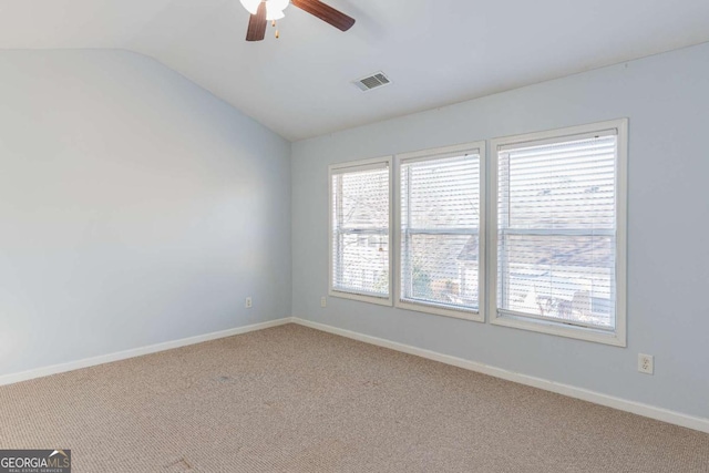 carpeted spare room with lofted ceiling, baseboards, visible vents, and ceiling fan