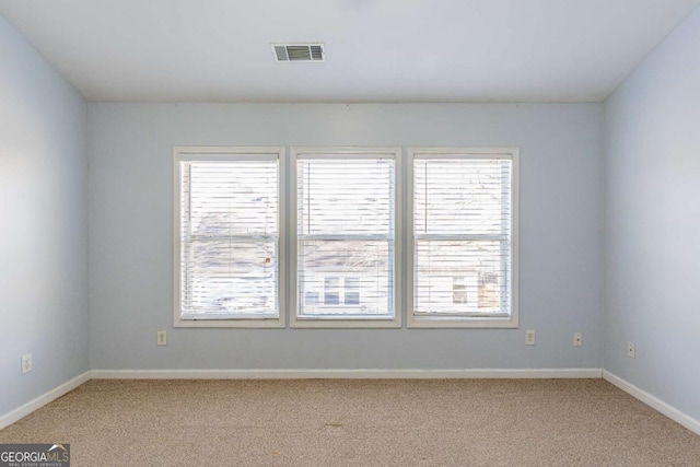 spare room featuring light carpet, visible vents, a healthy amount of sunlight, and baseboards