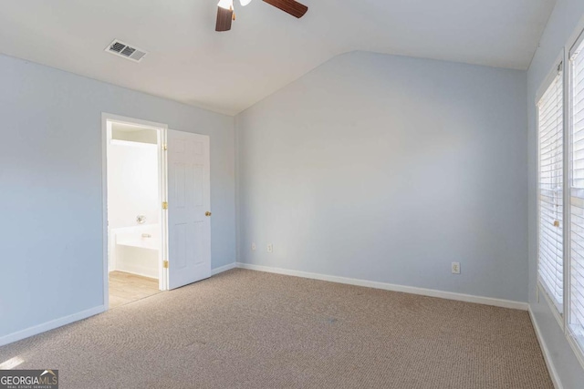 carpeted spare room featuring a ceiling fan, vaulted ceiling, baseboards, and visible vents