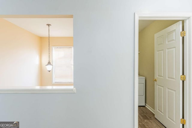 hall featuring washer / dryer, wood finished floors, and baseboards