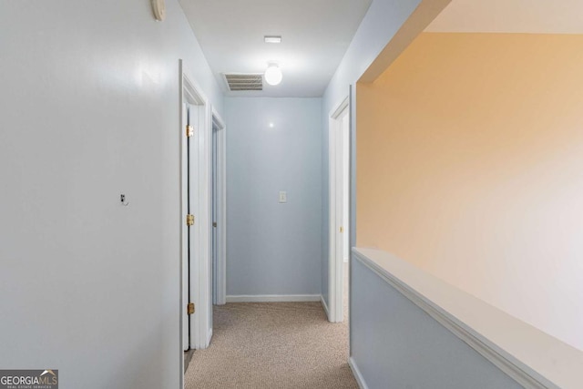 corridor featuring visible vents, baseboards, and light colored carpet