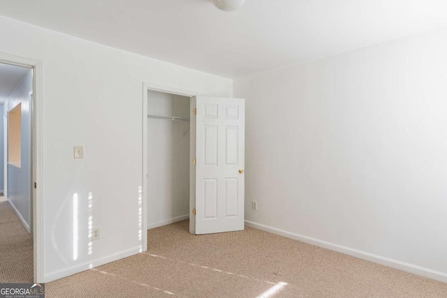 unfurnished bedroom with baseboards, carpet floors, and a closet