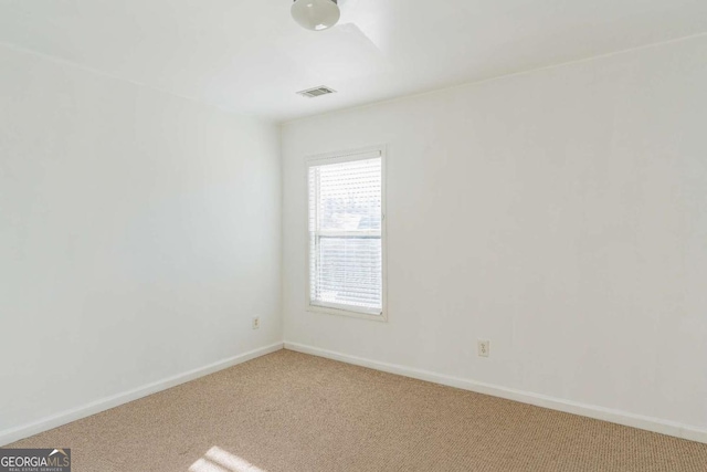 spare room featuring carpet flooring, visible vents, and baseboards