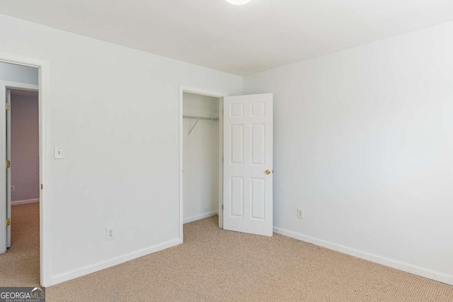 unfurnished bedroom with light colored carpet, baseboards, and a closet