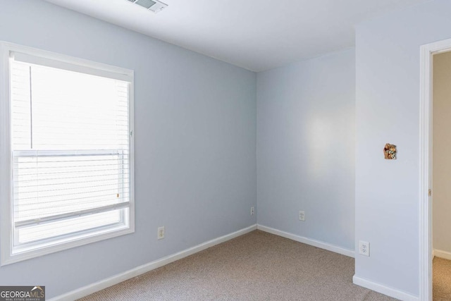 carpeted spare room featuring visible vents and baseboards